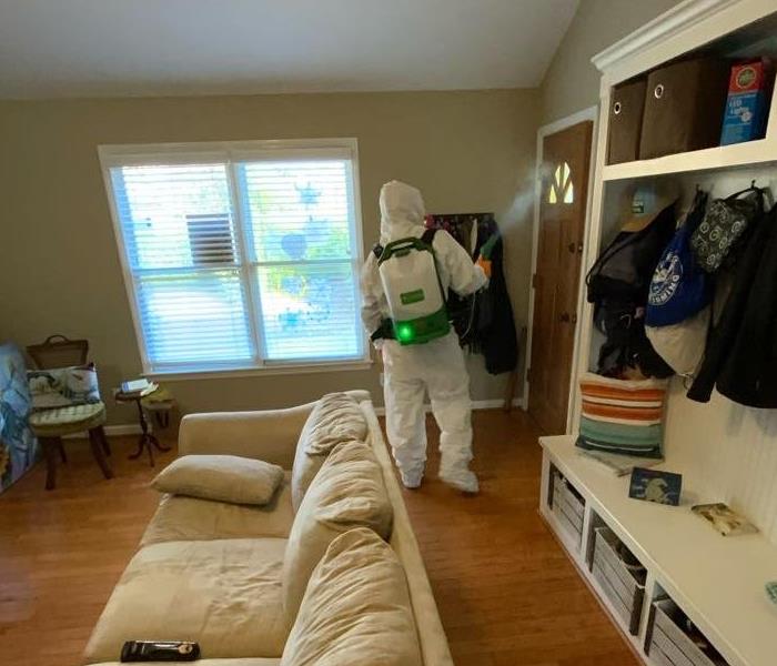 photo of a production member in full PPE cleaning residential home 